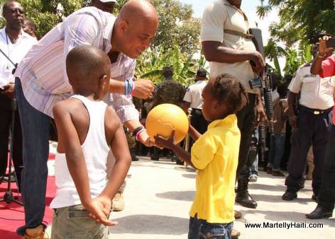 President Martelly fe yon timoun kado yon boul pandan inauguration yon pon nan Arcahaie Haiti